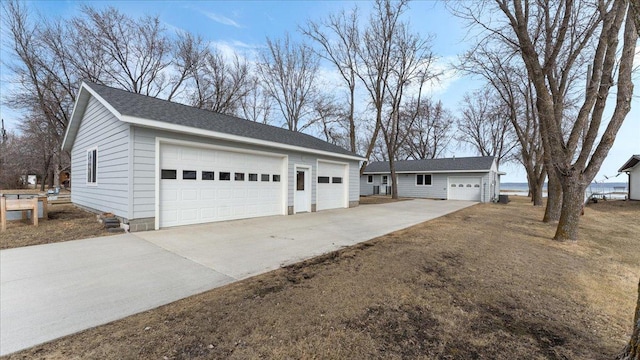 view of front of property featuring a detached garage, an outbuilding, and roof with shingles