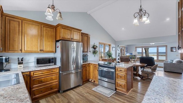 kitchen with stainless steel appliances, brown cabinets, a notable chandelier, and open floor plan