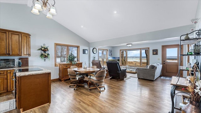 dining room featuring high vaulted ceiling, wood finished floors, an inviting chandelier, a toaster, and baseboards