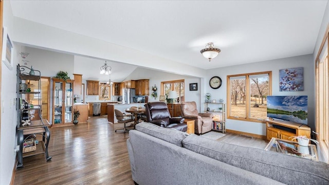 living room featuring vaulted ceiling, baseboards, and wood finished floors