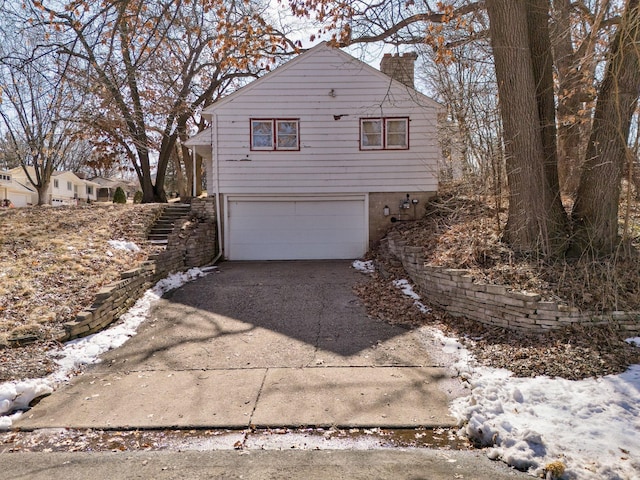 exterior space featuring a garage, concrete driveway, and a chimney