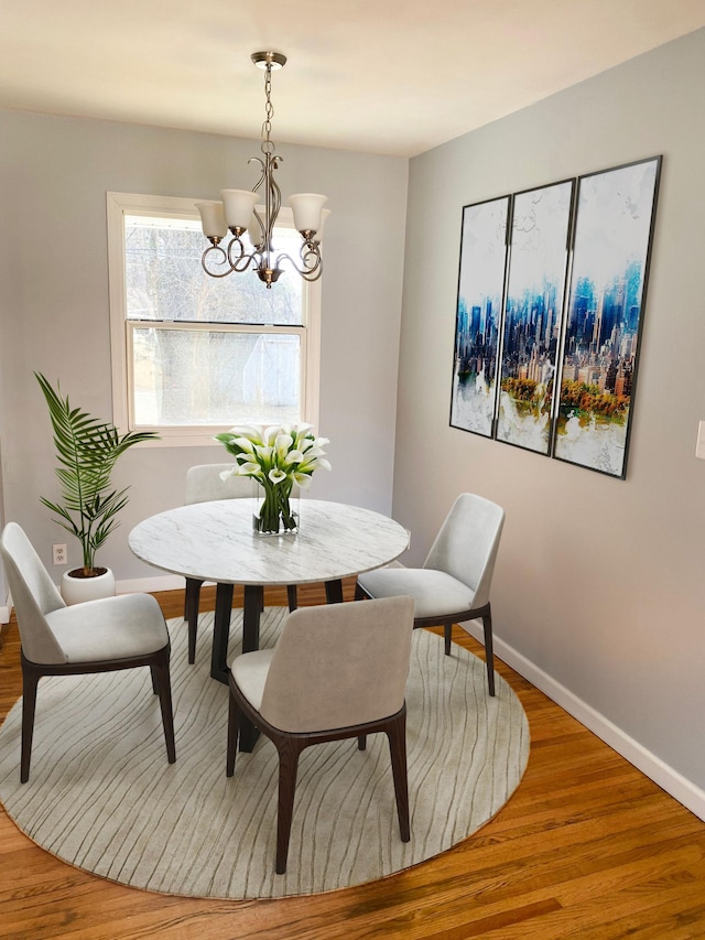 dining room with baseboards, a notable chandelier, and wood finished floors