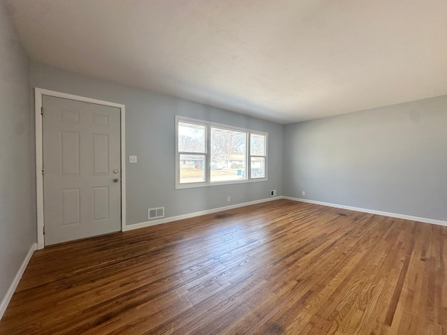 unfurnished living room featuring wood finished floors, visible vents, and baseboards