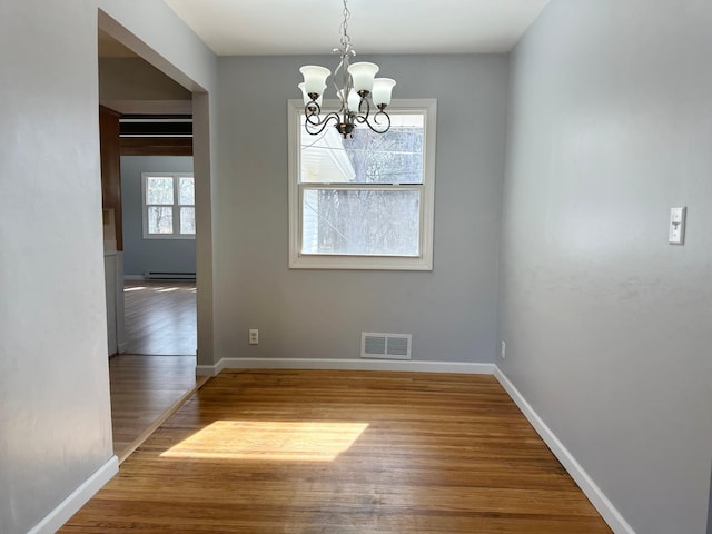 unfurnished dining area with visible vents, baseboards, an inviting chandelier, and wood finished floors