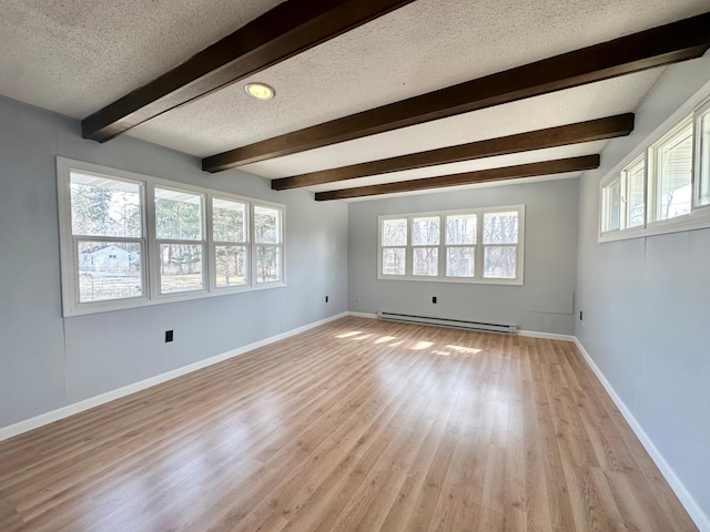 unfurnished room with a healthy amount of sunlight, baseboards, baseboard heating, and a textured ceiling