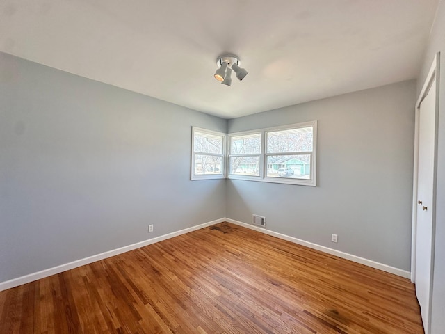 unfurnished bedroom featuring a closet, visible vents, baseboards, and wood finished floors