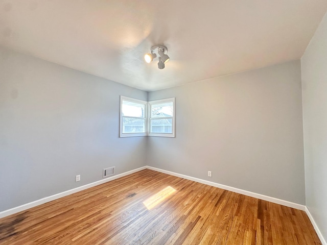 empty room featuring light wood-type flooring, visible vents, and baseboards