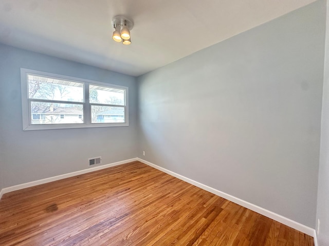 unfurnished room featuring visible vents, baseboards, and wood finished floors