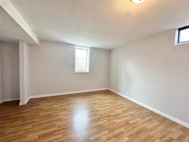 below grade area featuring baseboards, plenty of natural light, and light wood-style flooring