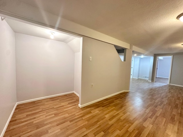 empty room with visible vents, baseboards, a textured ceiling, and wood finished floors