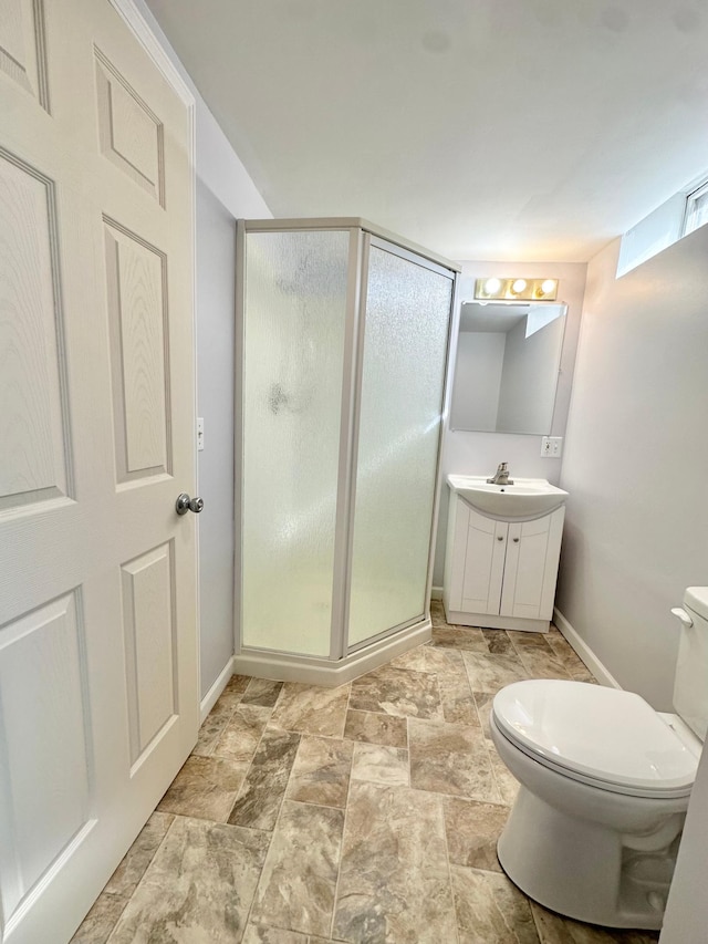 full bathroom with vanity, baseboards, a stall shower, stone finish flooring, and toilet