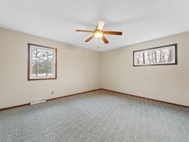 unfurnished room with visible vents, ceiling fan, baseboards, carpet, and a textured ceiling