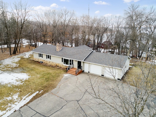 view of front facade with roof with shingles, a chimney, a front lawn, a garage, and aphalt driveway