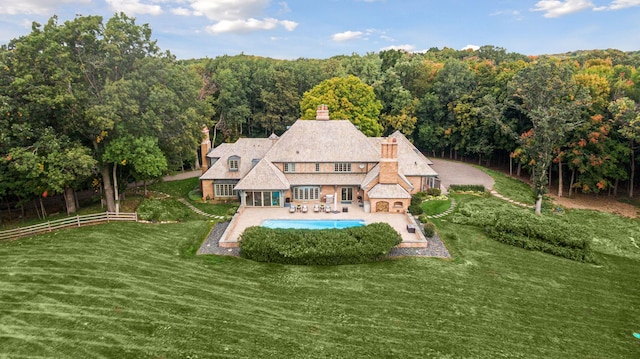 rear view of property featuring a patio, fence, a yard, a fenced in pool, and a chimney