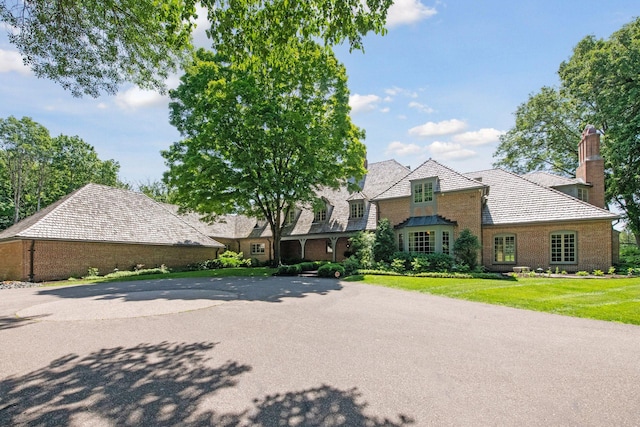 view of front facade with a front lawn, brick siding, and a chimney