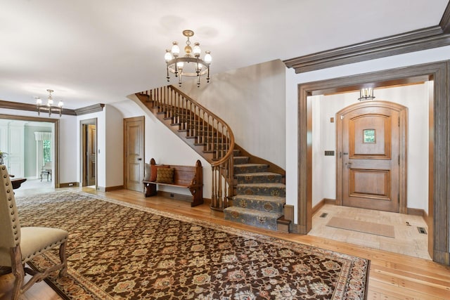 entryway featuring stairway, a notable chandelier, wood finished floors, and crown molding