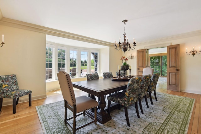 dining room featuring a notable chandelier, a healthy amount of sunlight, light wood-style flooring, and crown molding