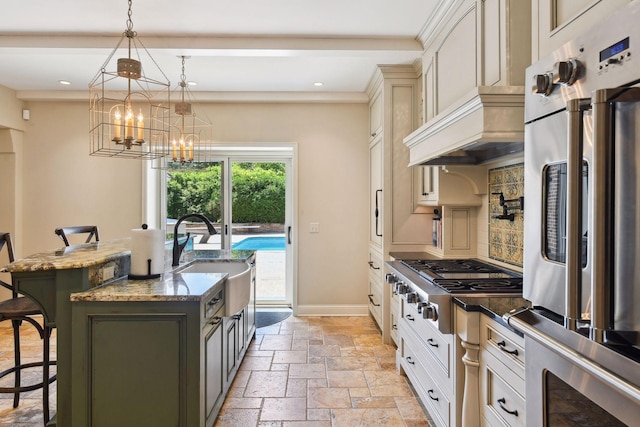 kitchen featuring a center island with sink, a kitchen bar, stone tile floors, appliances with stainless steel finishes, and a sink