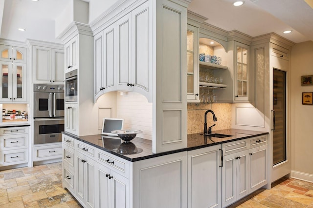 kitchen with a sink, double oven, recessed lighting, and stone tile flooring