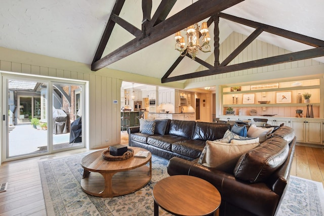 living room with wooden walls, high vaulted ceiling, beam ceiling, light wood-style flooring, and a chandelier