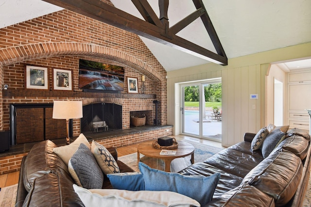 living area featuring lofted ceiling with beams, a brick fireplace, wood finished floors, and brick wall