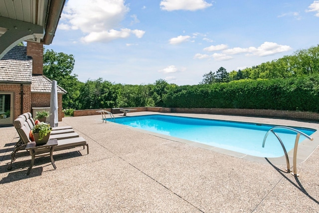 view of swimming pool featuring a patio, a fenced in pool, and a diving board