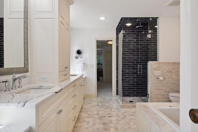 bathroom featuring toilet, a stall shower, a sink, recessed lighting, and double vanity