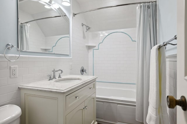 bathroom featuring toilet, vanity, tile walls, and shower / tub combo