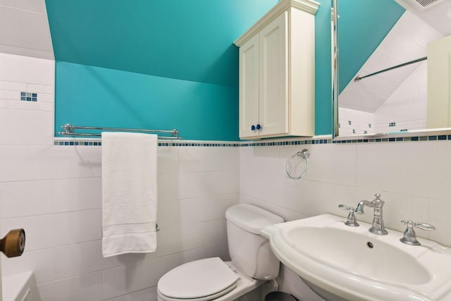 bathroom featuring vaulted ceiling, toilet, tile walls, and a sink