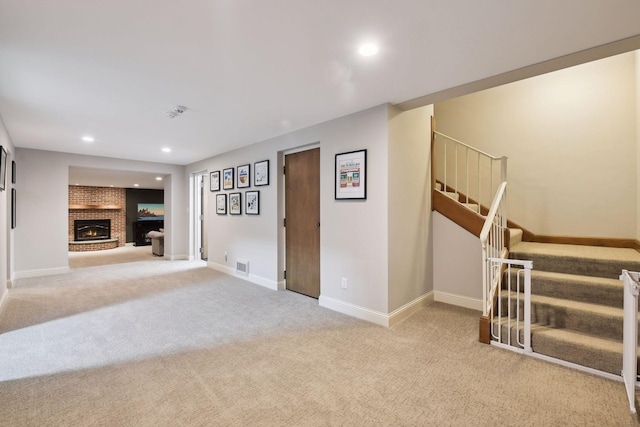 unfurnished living room featuring visible vents, baseboards, stairway, carpet floors, and a fireplace