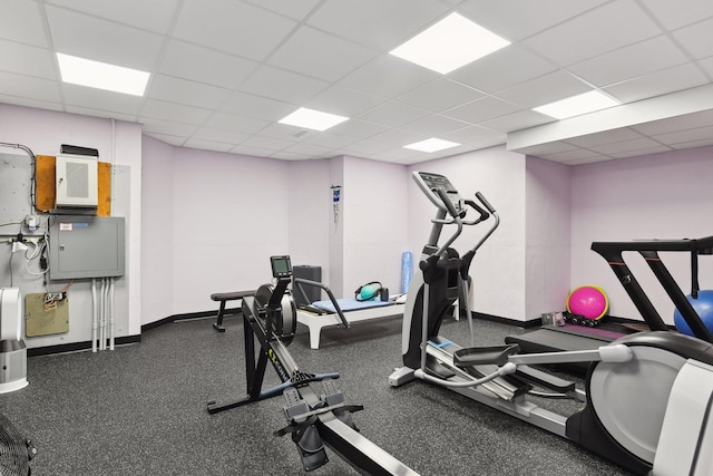 exercise room with baseboards and a paneled ceiling