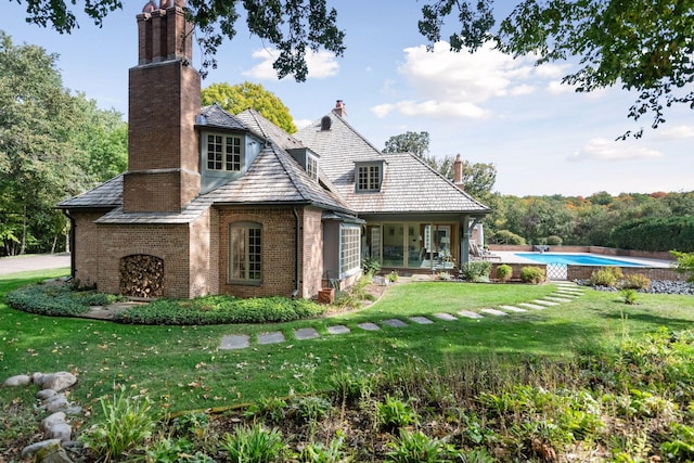 exterior space featuring brick siding, a chimney, and a front lawn