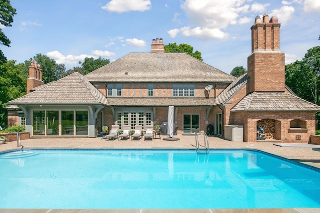 outdoor pool with a patio and a fireplace