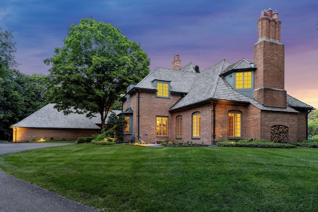 view of front of house featuring brick siding, a chimney, and a front lawn