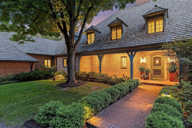 view of front of property featuring brick siding and a yard