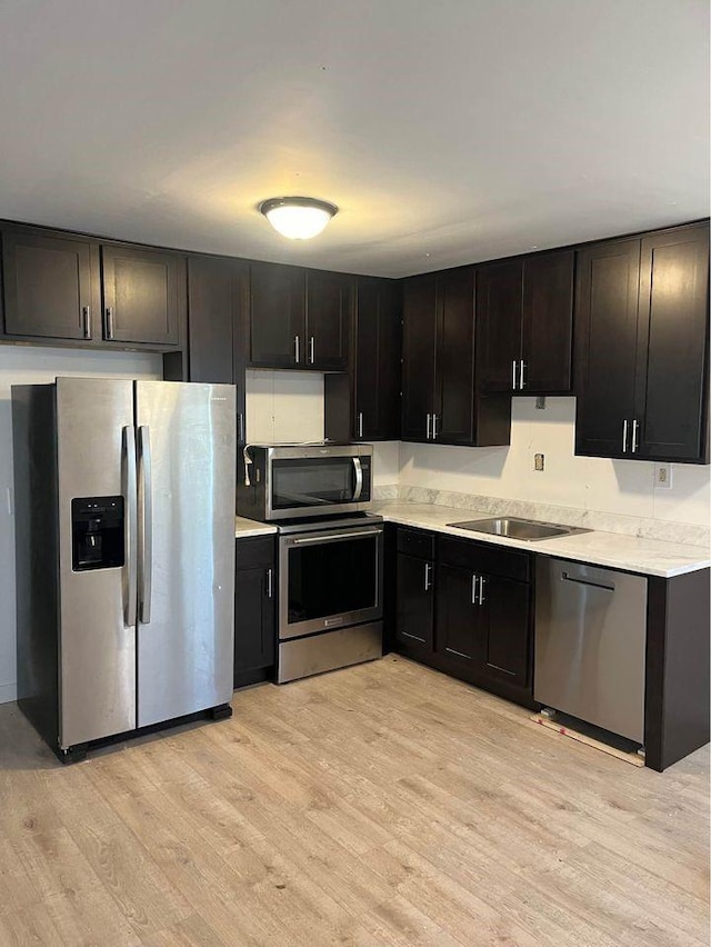 kitchen with light countertops, light wood-style floors, appliances with stainless steel finishes, and a sink