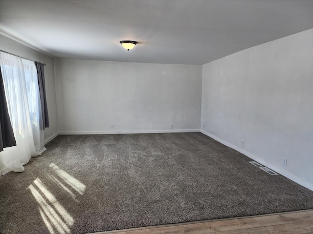 carpeted spare room featuring visible vents and baseboards