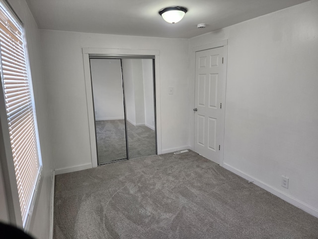 unfurnished bedroom featuring carpet, baseboards, and a closet