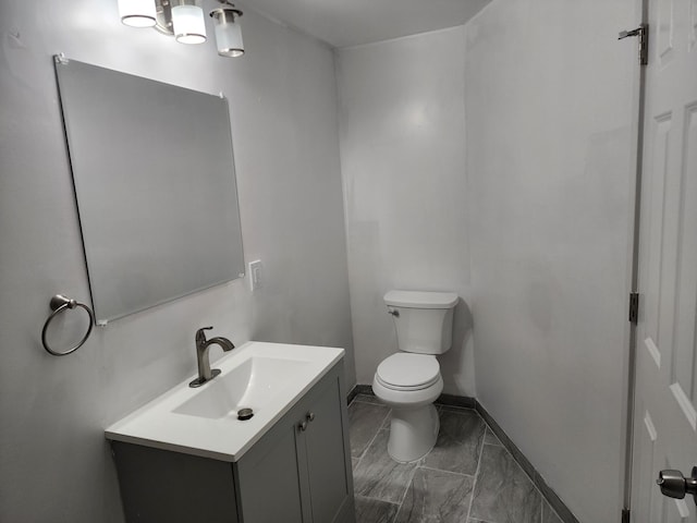 half bath with vanity, toilet, and baseboards