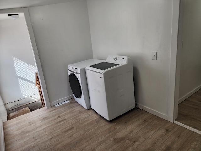 laundry area featuring baseboards, light wood-style flooring, laundry area, and washing machine and clothes dryer