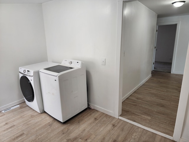 laundry room featuring baseboards, light wood finished floors, visible vents, laundry area, and separate washer and dryer