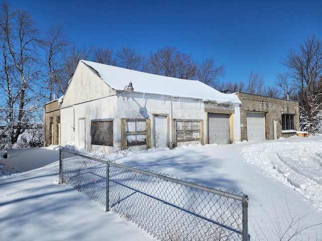 snow covered garage featuring fence