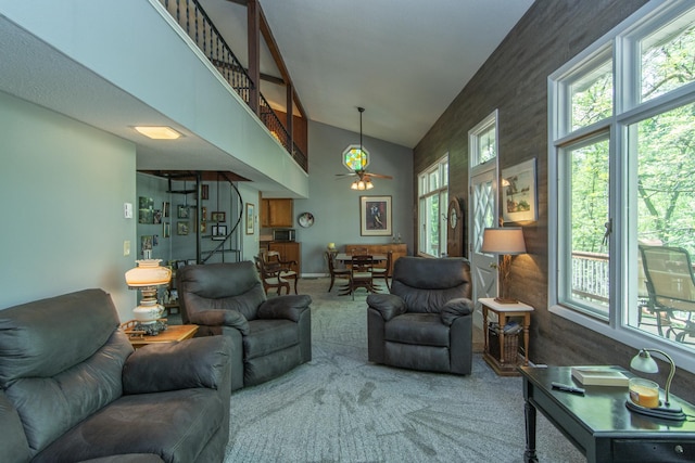 living area with ceiling fan, a high ceiling, and carpet flooring