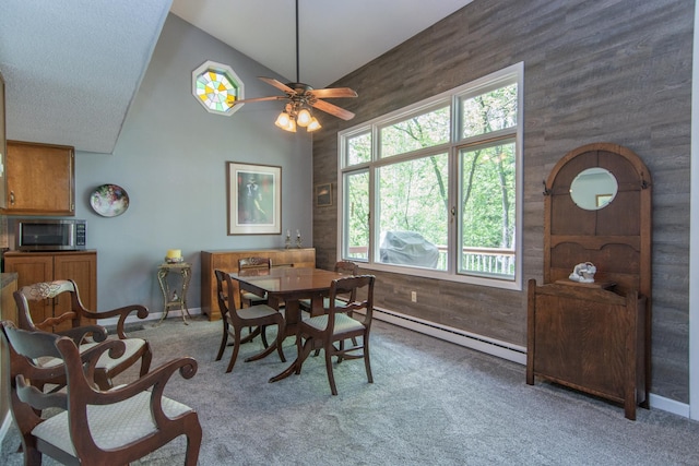 carpeted dining room featuring baseboards, a ceiling fan, a baseboard radiator, wood walls, and high vaulted ceiling