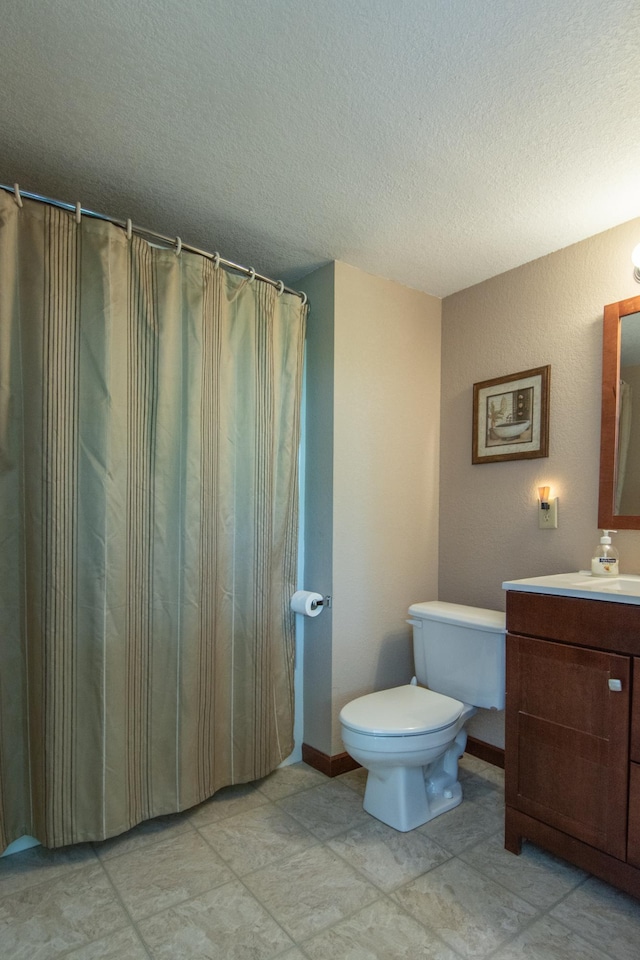 bathroom featuring toilet, a textured ceiling, vanity, and baseboards