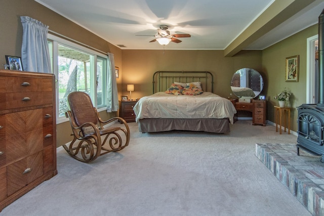 bedroom featuring a wood stove, ceiling fan, and carpet floors