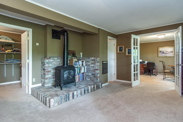 carpeted living room featuring french doors, baseboards, crown molding, and a wood stove