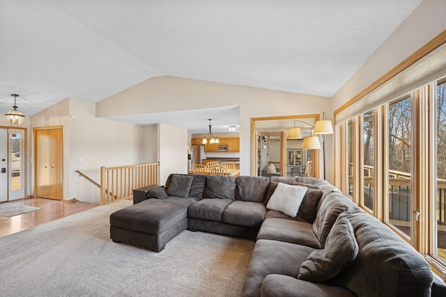 living area with vaulted ceiling, a notable chandelier, and wood finished floors