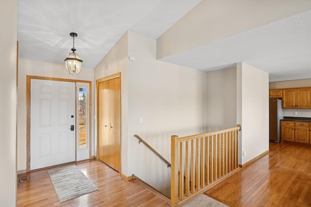 entrance foyer featuring light wood finished floors, an inviting chandelier, baseboards, and lofted ceiling