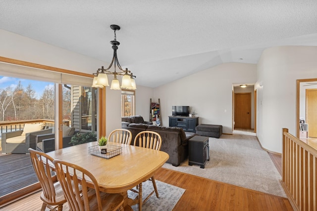 dining space featuring light wood finished floors, a textured ceiling, a chandelier, and vaulted ceiling